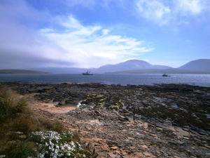 The European Marine Energy Centre (EMEC) is based at Stromness. A wave energy trials area is located on the west coast of Mainland Island with several devices on test. Here two of the support vessels are returning from the trials area via Hoy Sound against the back drop of Hoy island, the most mountainous of the islands. The Devonian sandstone "pavement" formation in the rocks in the foreshore is typical of this area of the Mainland Island